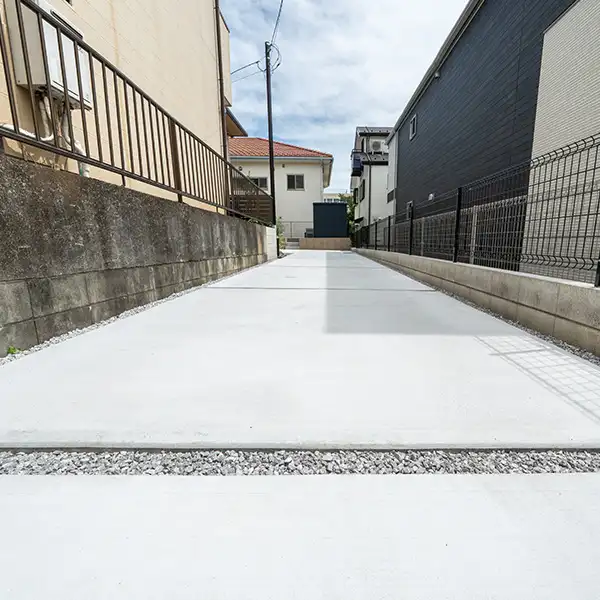塀に挟まれた細長い敷地を、土間コンクリートで仕上げた縦長の駐車場の参考例
